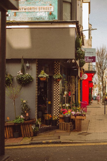 A floral shop on Old Malden High Street with a display of fresh flower arrangements and potted plants outside the entrance. The arrangement includes a variety of colourful blooms such as pink, yellow,