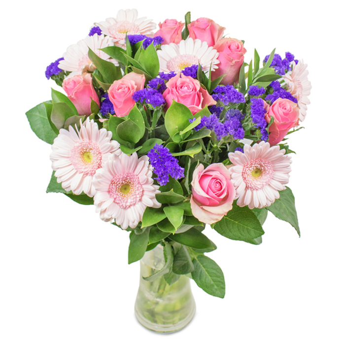 Presenting a vibrant and elegantly balanced bouquet arranged in a clear glass vase, this composition radiates the gentle spirit of Old Malden. Approximately 7-9 classic spiral pink roses form the focal point-some with tightly furled petals, others just opening to reveal their soft, satiny texture. Around them are 5-7 pale pink gerbera daisies, each with a luminous, almost creamy centre and wide, welcoming petals. In between, clusters of bright purple statice add textural interest and a splash of deeper colour, recalling the lively flower markets at Old Malden's edges. Supporting everything is a bed of deep green foliage-glossy, abundant, and reminiscent of the lush parks nearby. Light from a window streams through the vase, illuminating the fresh stems and clear water, underscoring the bouquet's sense of purity and renewal. Such a gift is ideal for local birthdays, anniversaries, or as a centrepiece for family gatherings in homes along Manor Drive or Cambridge Avenue. With freshness and quality that evoke the attentiveness of Old Malden florists, this arrangement offers a visual poem of joy, celebration, and affection for any special moment or cherished friend.